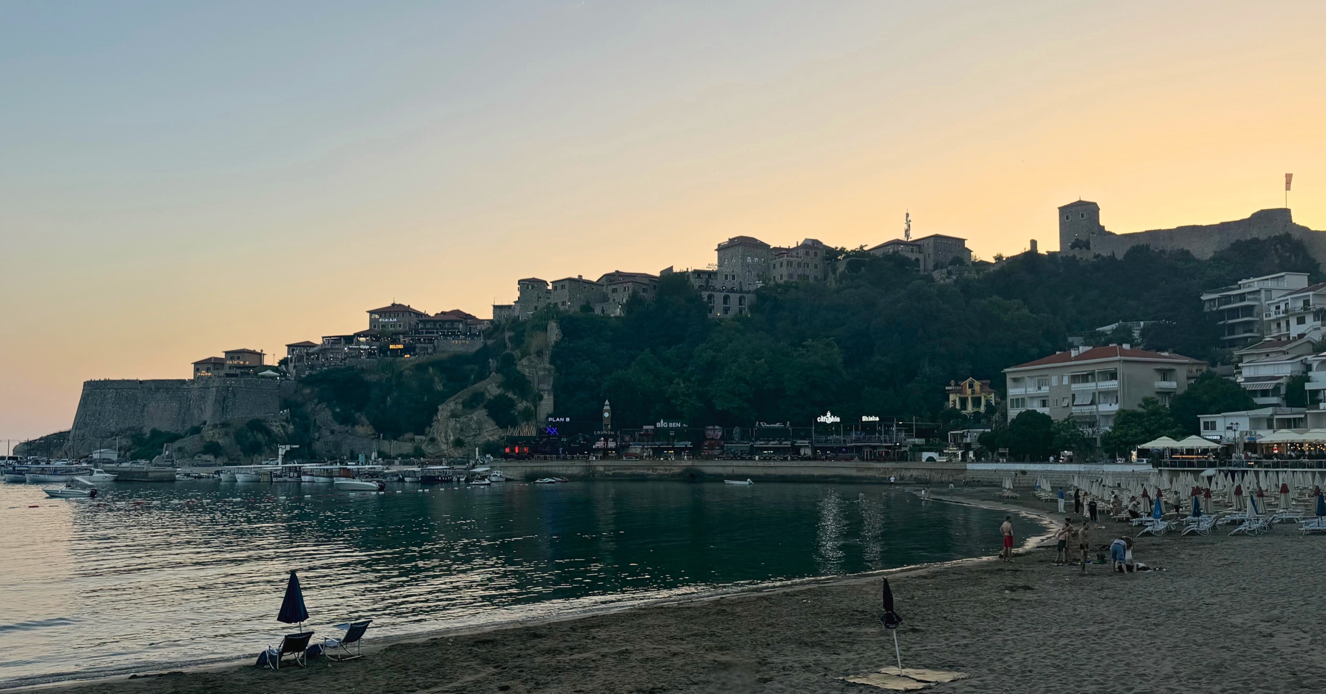 Ulcinj Old Town rising above Mala Plaža at sunset.