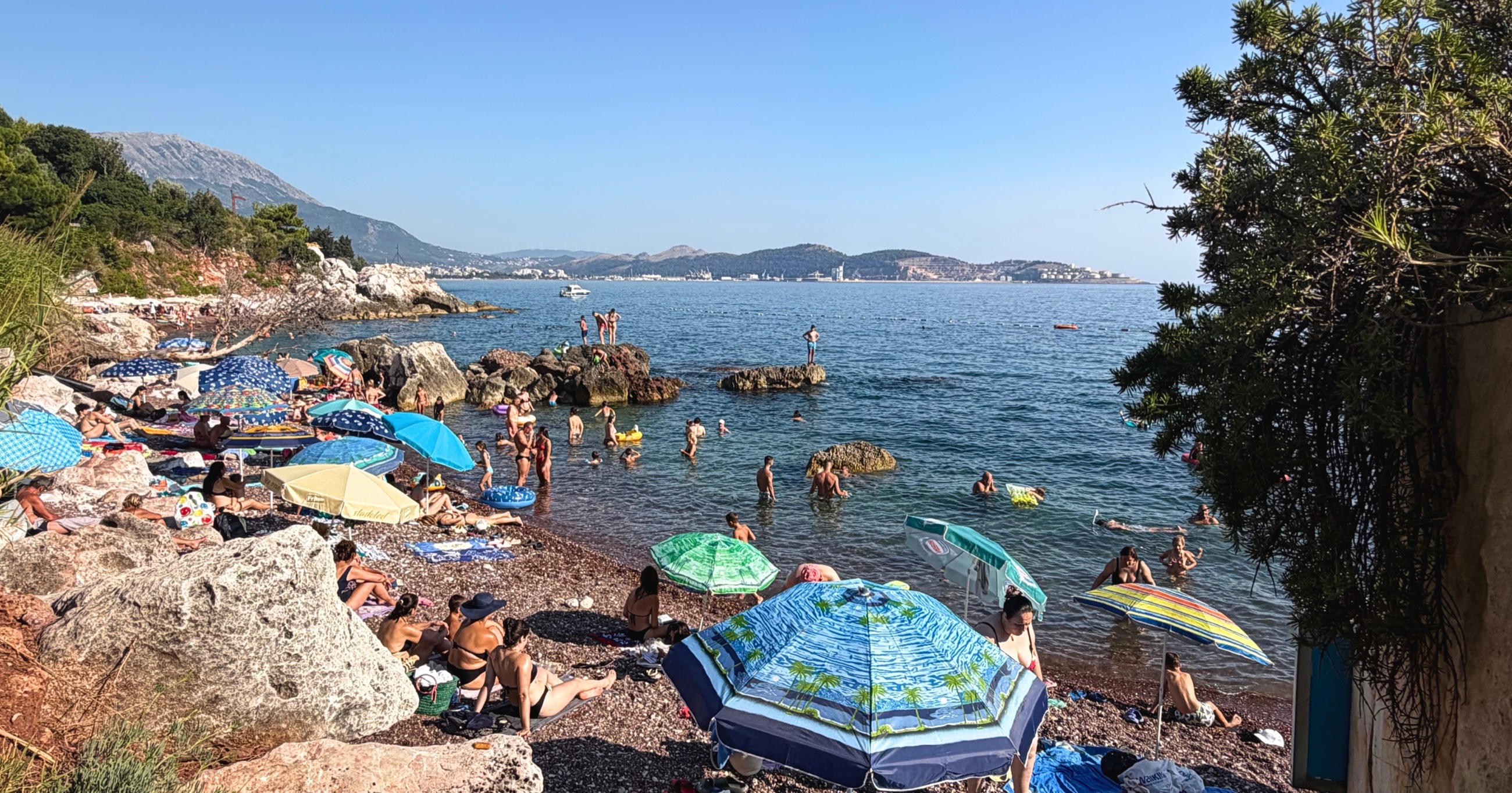 Red Beach near Bar, with swimmers and umbrellas among the rocks.