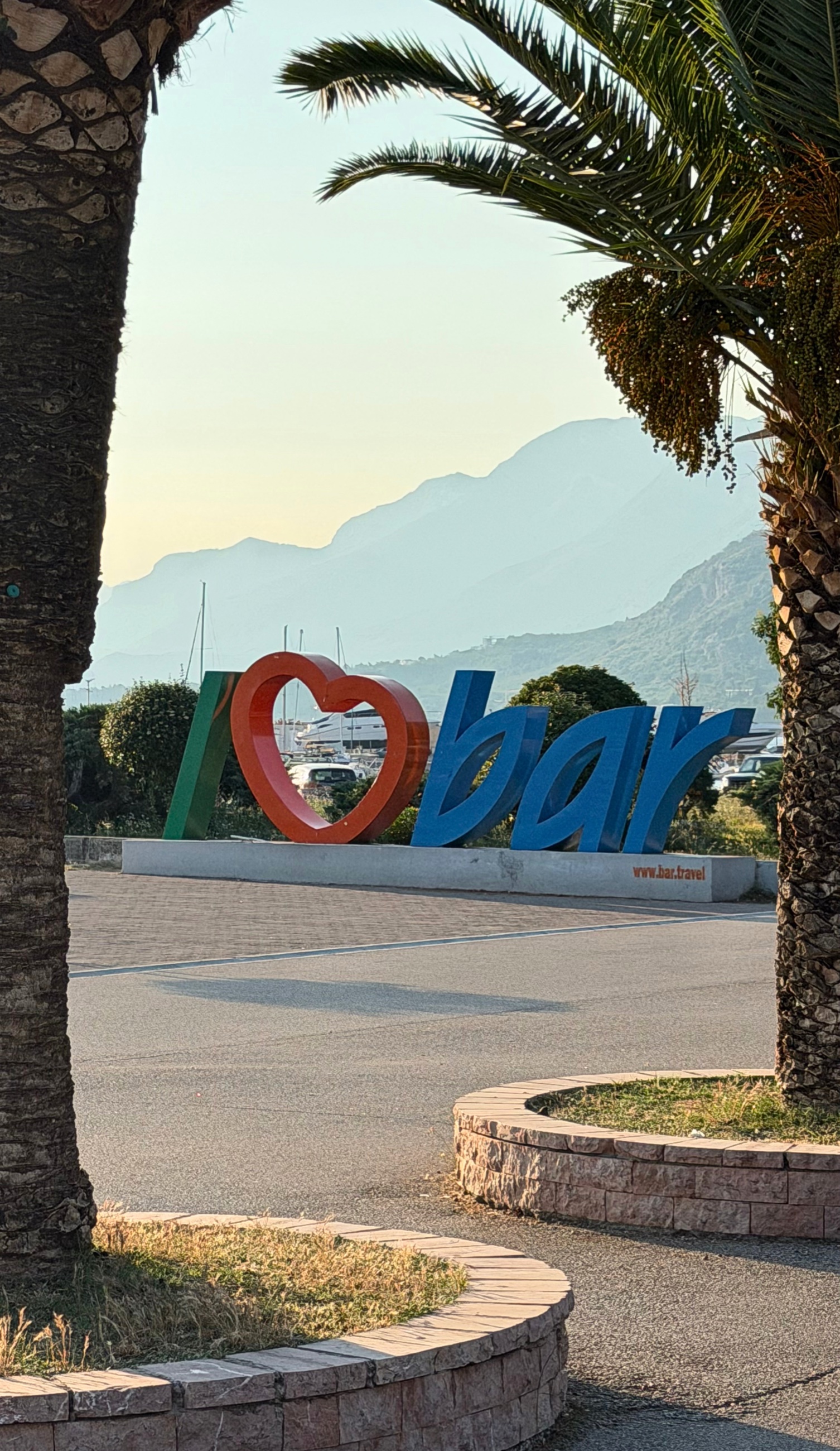The Bar sign near the marina, with palms and mountains behind it.