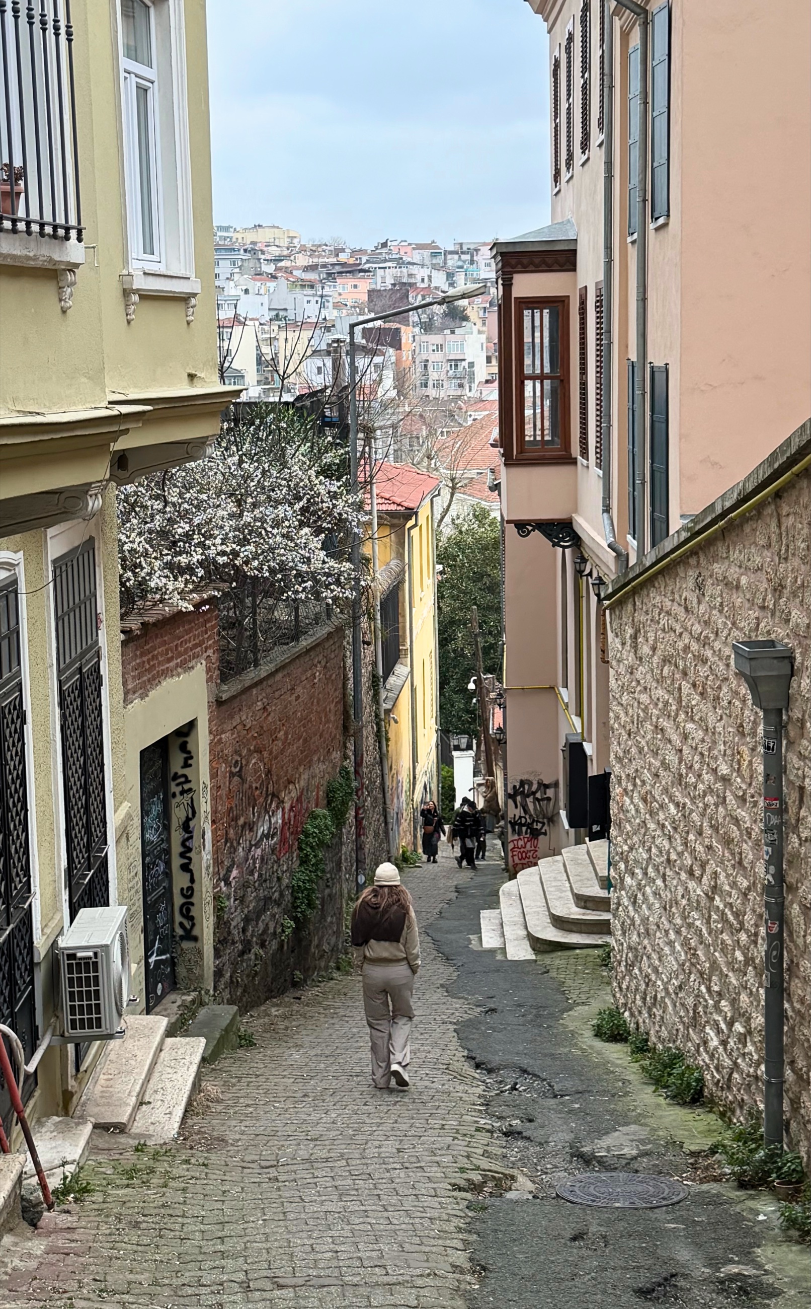 A narrow back street in Beyoğlu with steep pavement and surrounding buildings.