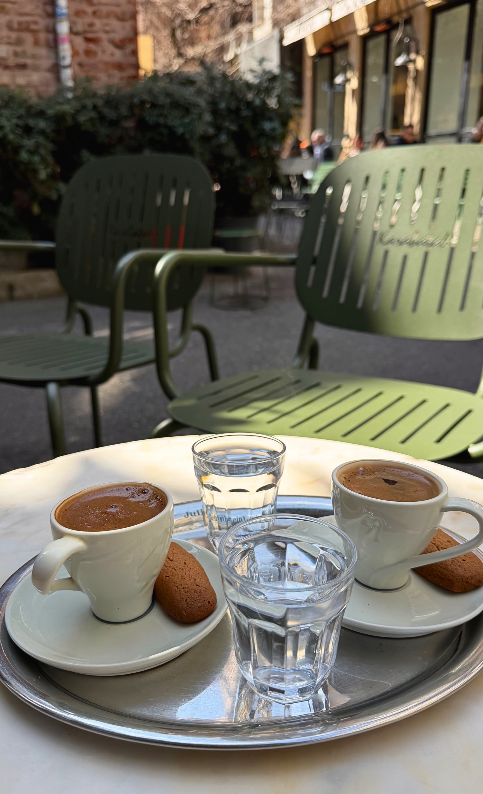 Two cups of Turkish coffee served on a metal tray outdoors.