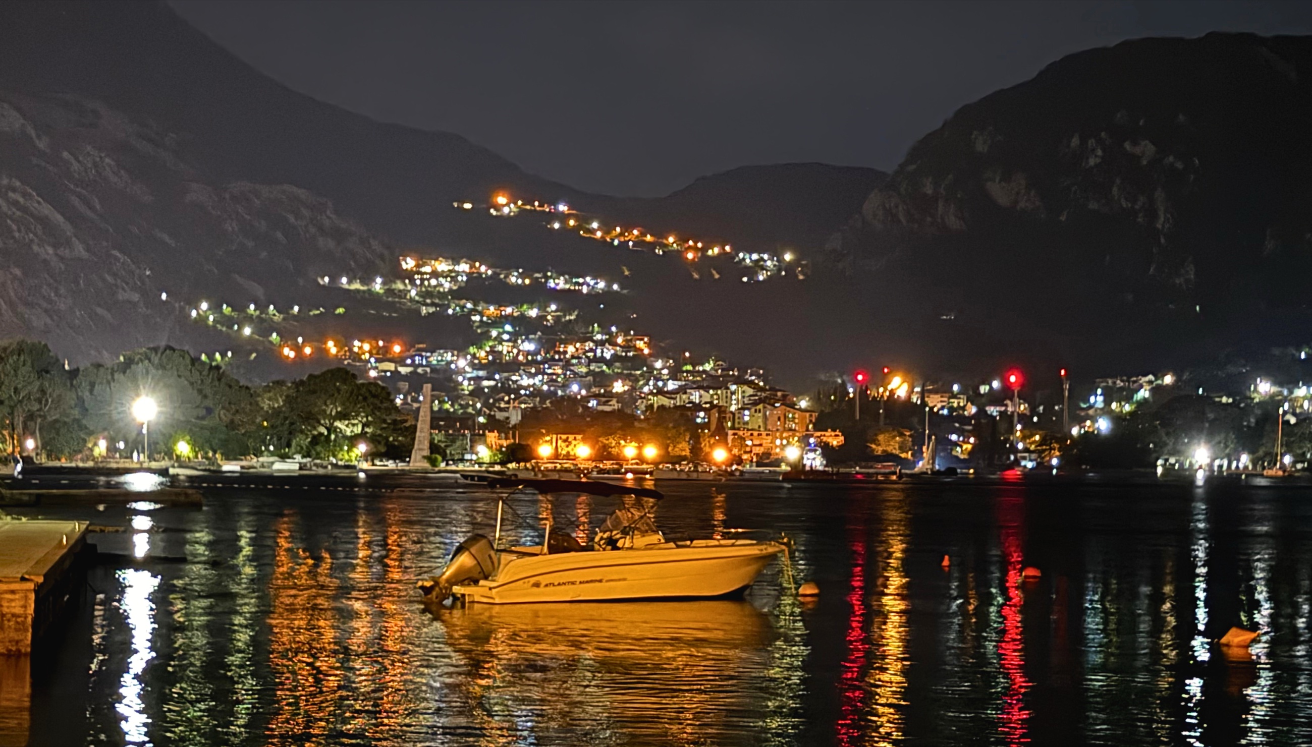 Kotor after dark, with harbor lights reflected across the bay beneath the mountains.