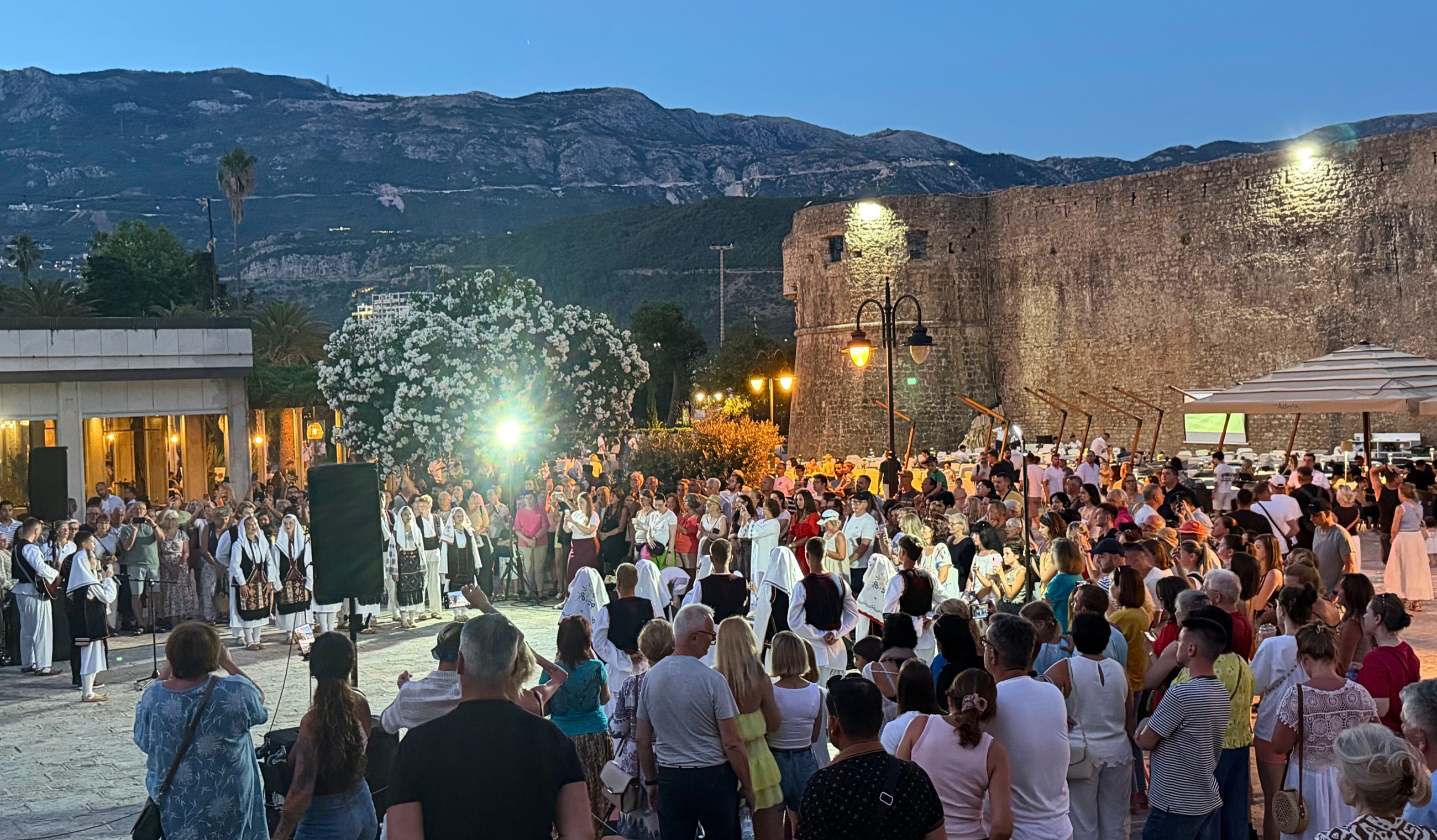 Evening music in Budva, with traditional dress, local song, and a crowd gathered beside the old walls as the town moved into night
