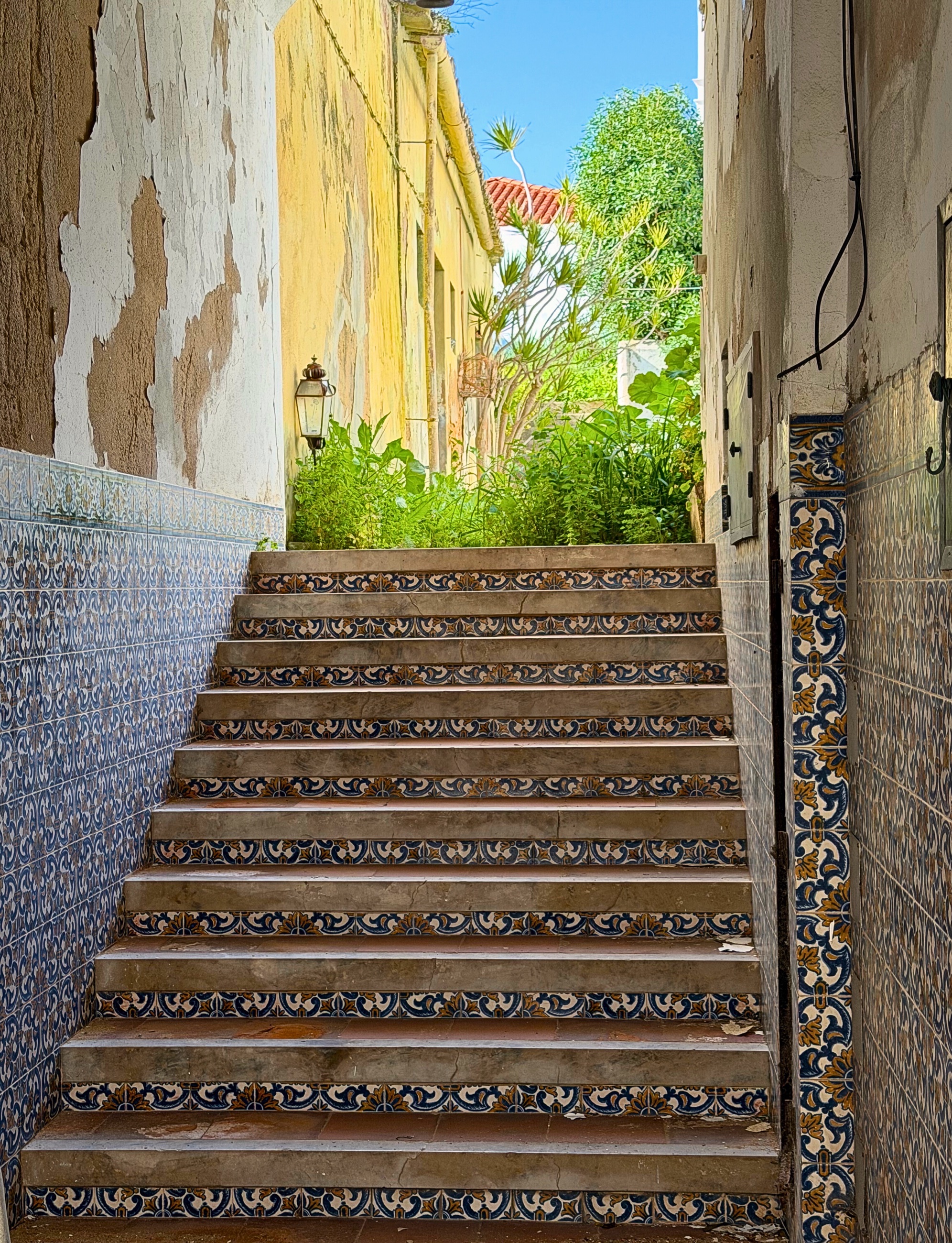 A tiled staircase in Lagos framed by old walls and greenery.