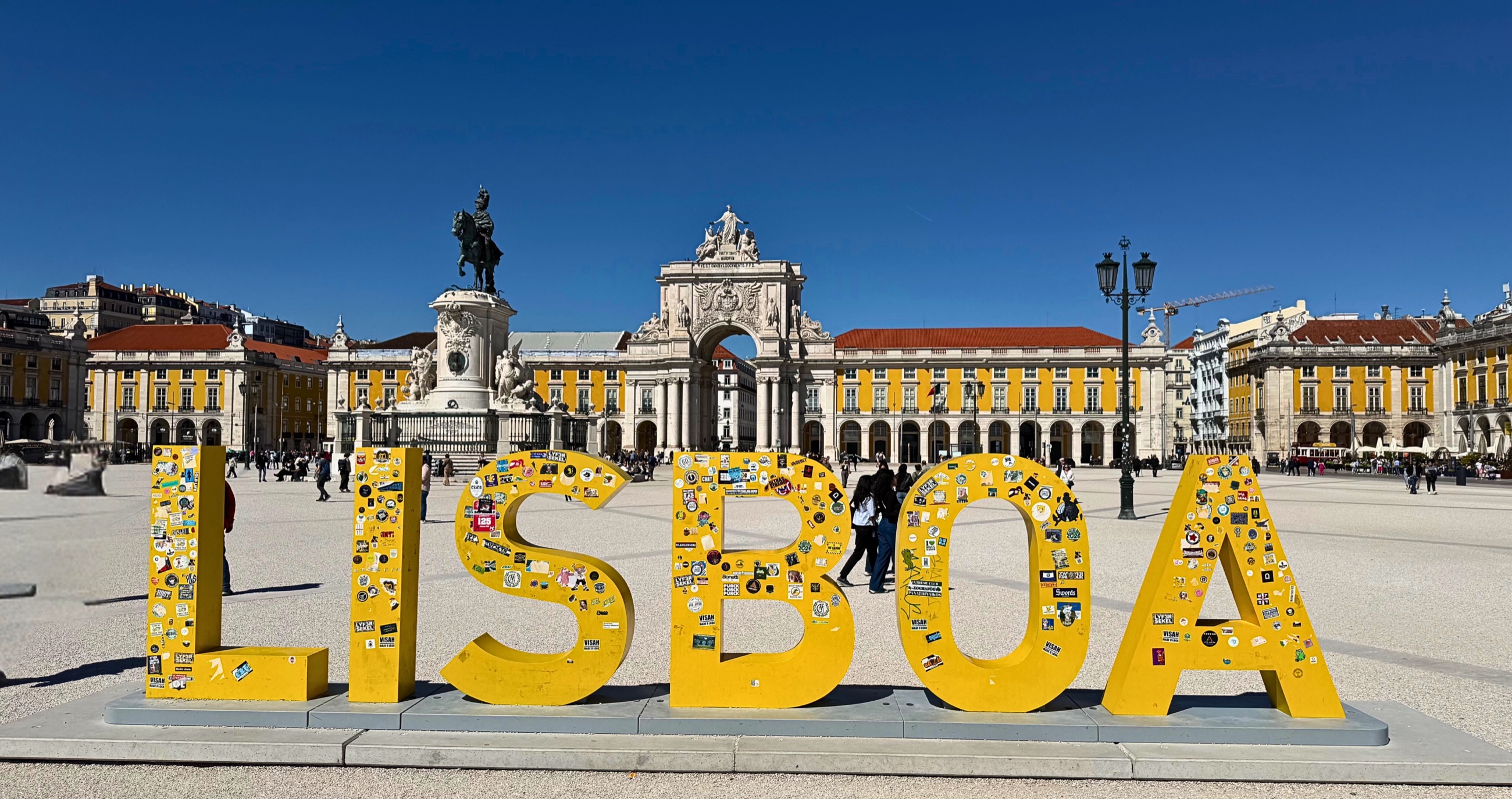 The yellow Lisboa sign in Praça do Comércio with the Arco da Rua Augusta behind it.