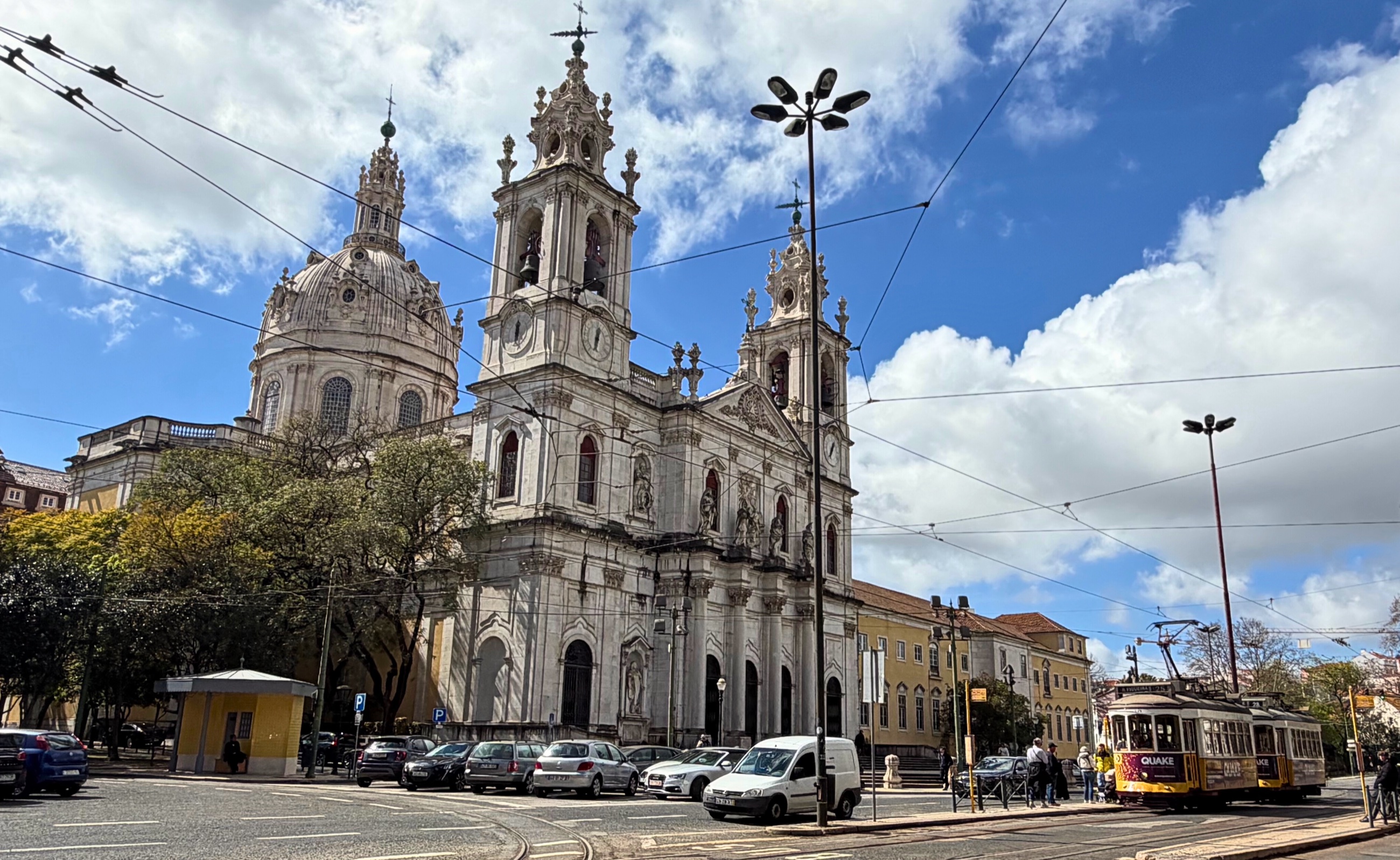 Basilica da Estrela in Lisbon viewed from the street, with its pale stone facade and towers rising above the city.