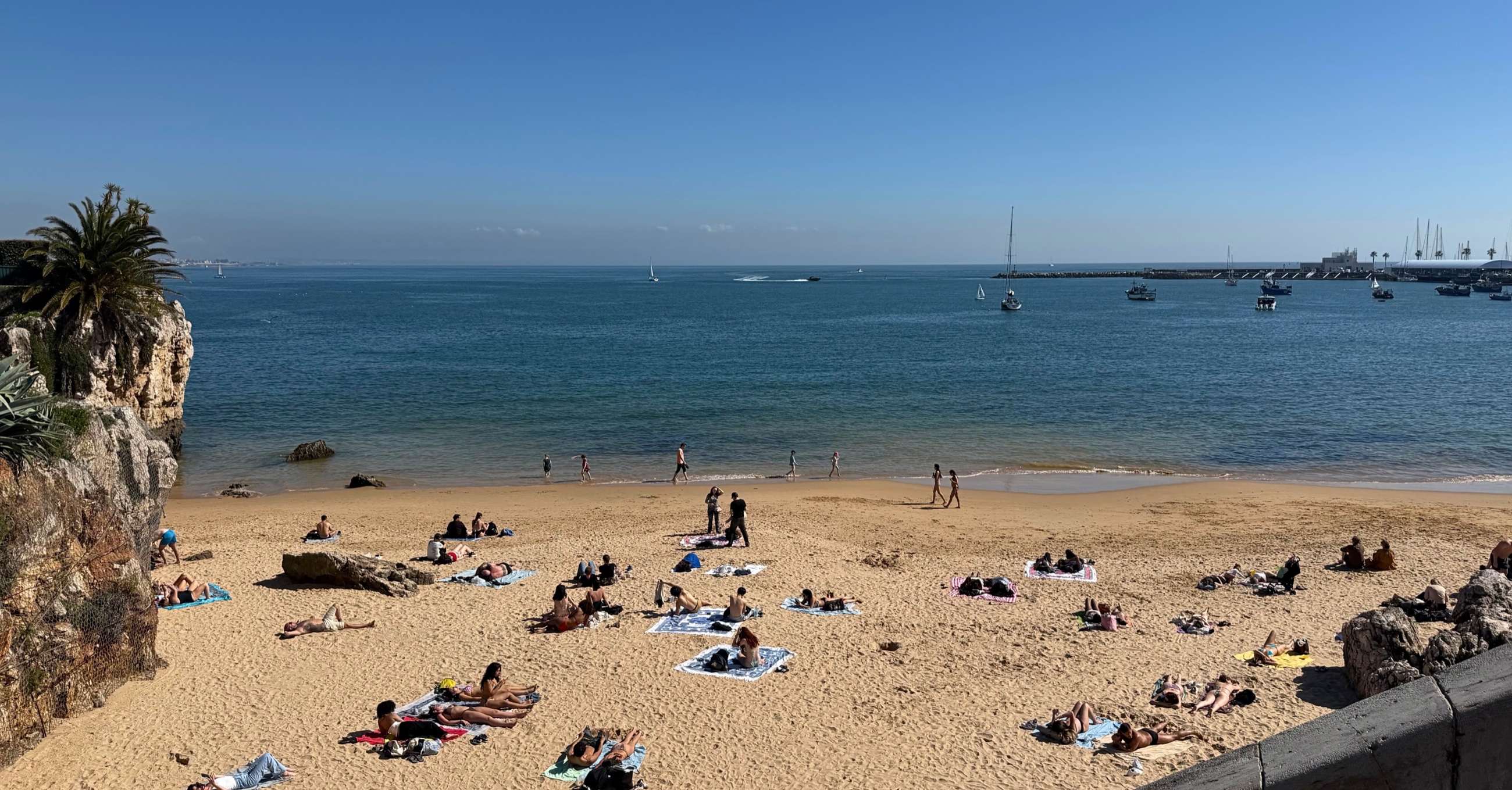 Praia da Rainha in Cascais with a small sandy beach tucked between rocky cliffs.