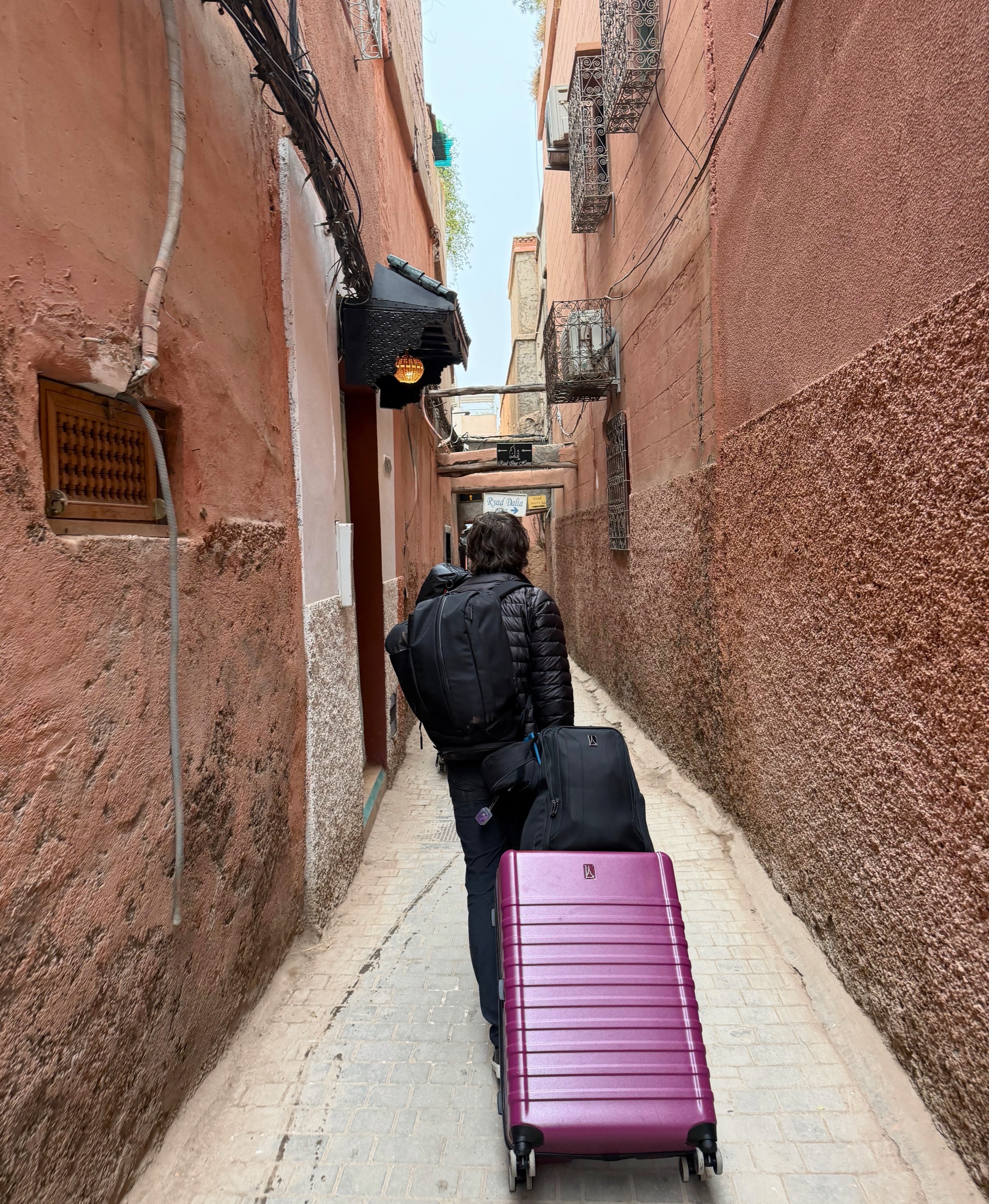 A narrow Marrakesh medina passage where pedestrians continue beyond the point where cars can enter.