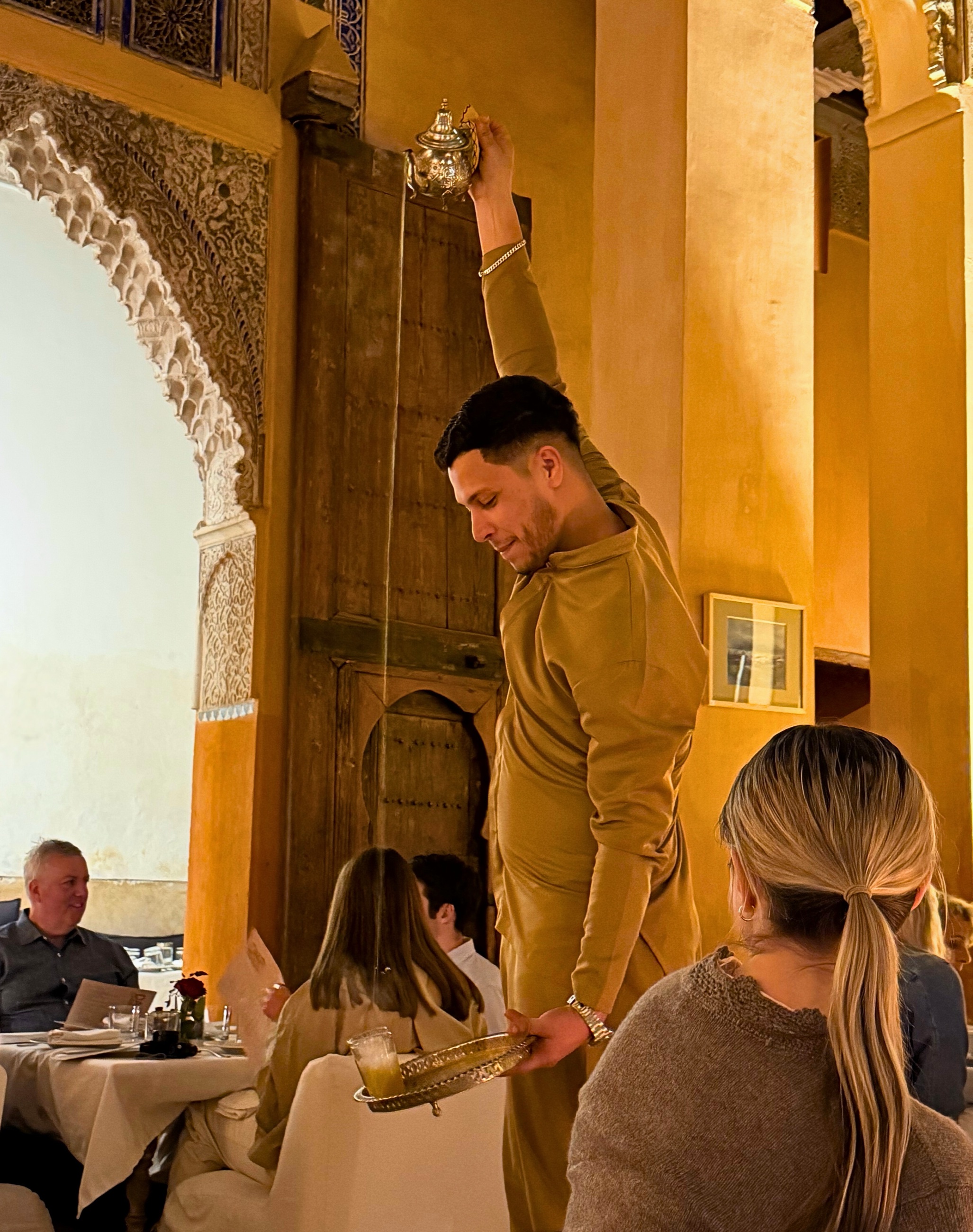 Moroccan mint tea being poured from a teapot into a glass.
