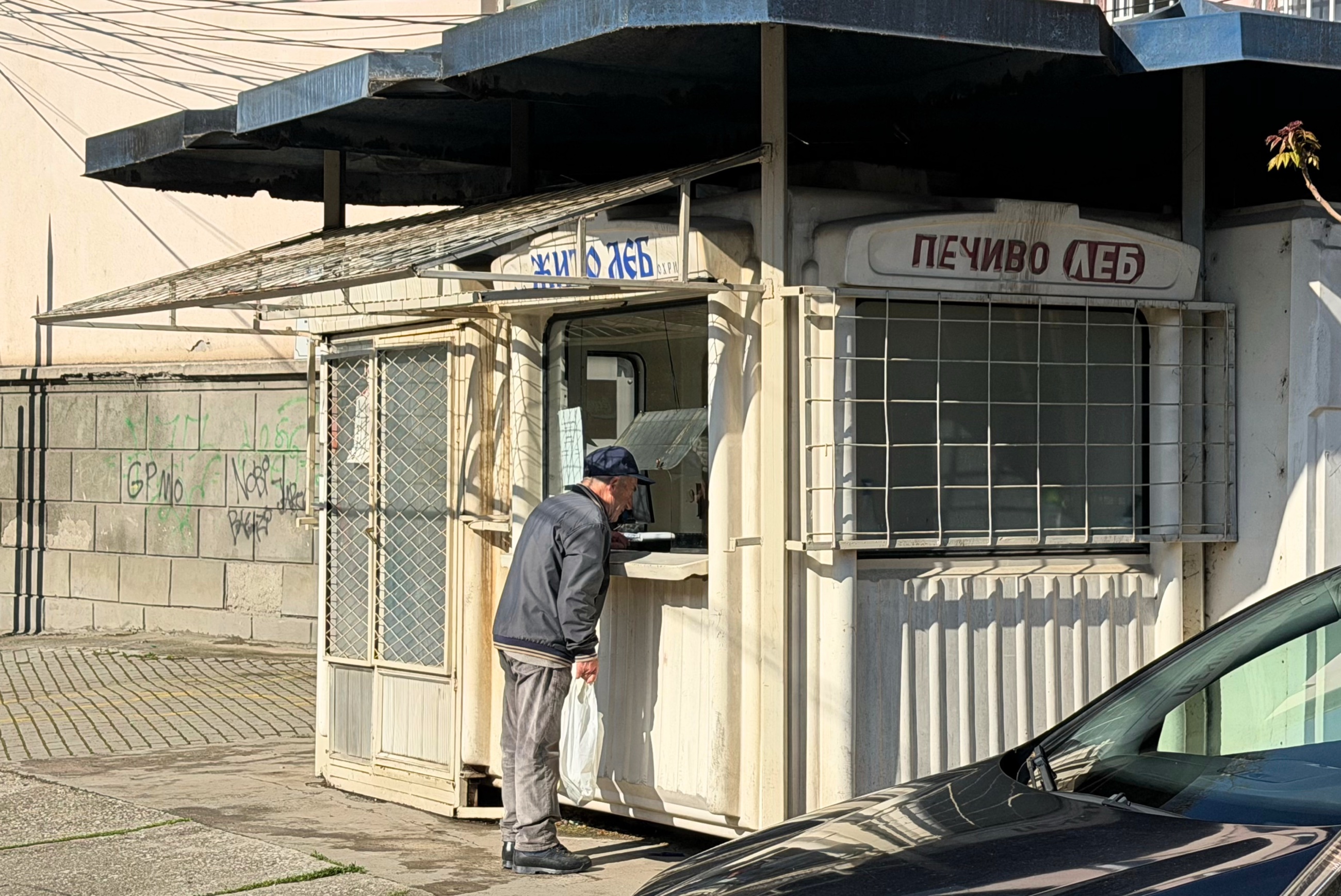 A man buying bread from a small neighborhood bread kiosk in Ohrid.