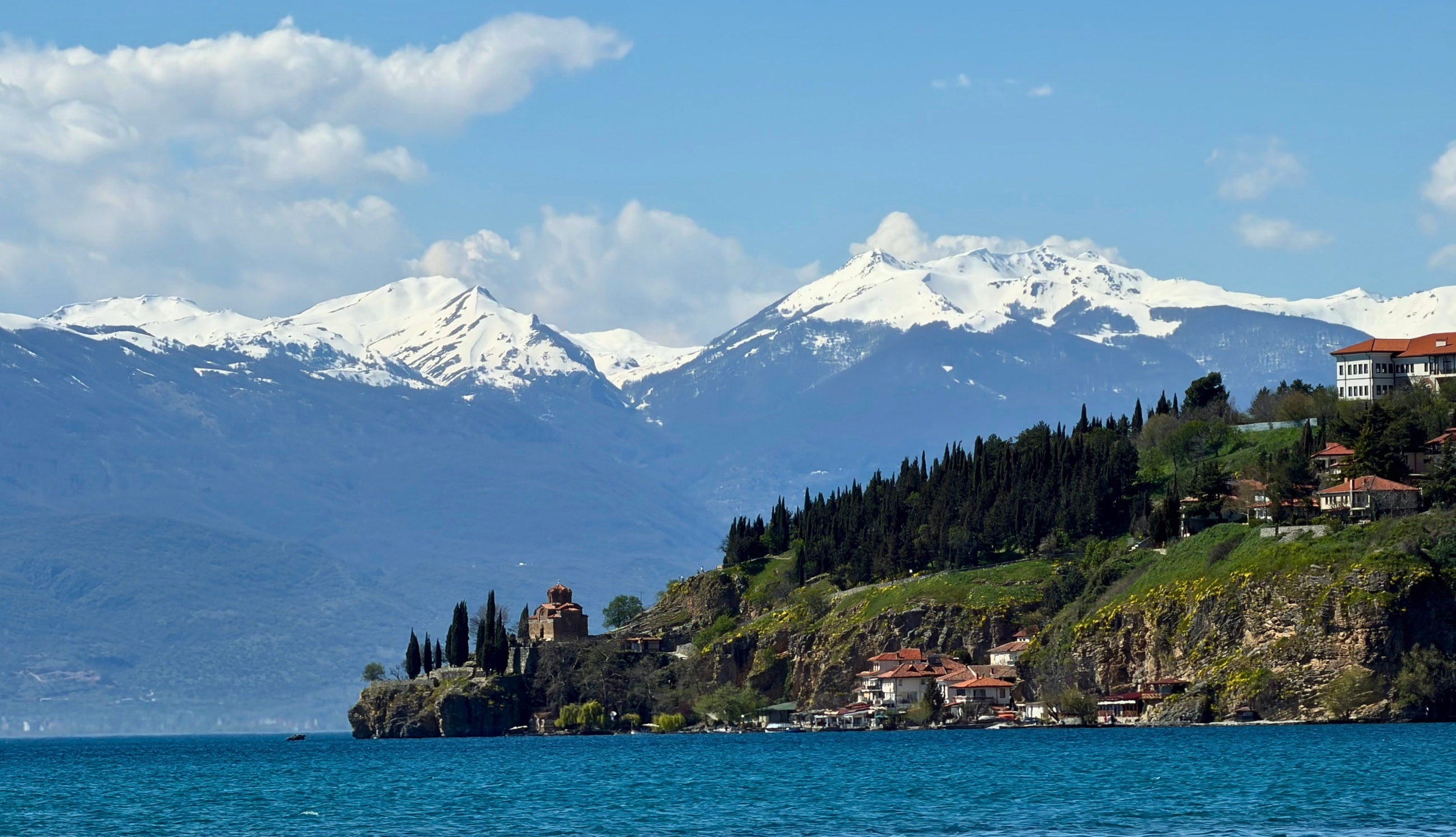 Lake Ohrid with churches, hillside buildings, and snow-covered mountains in the distance.