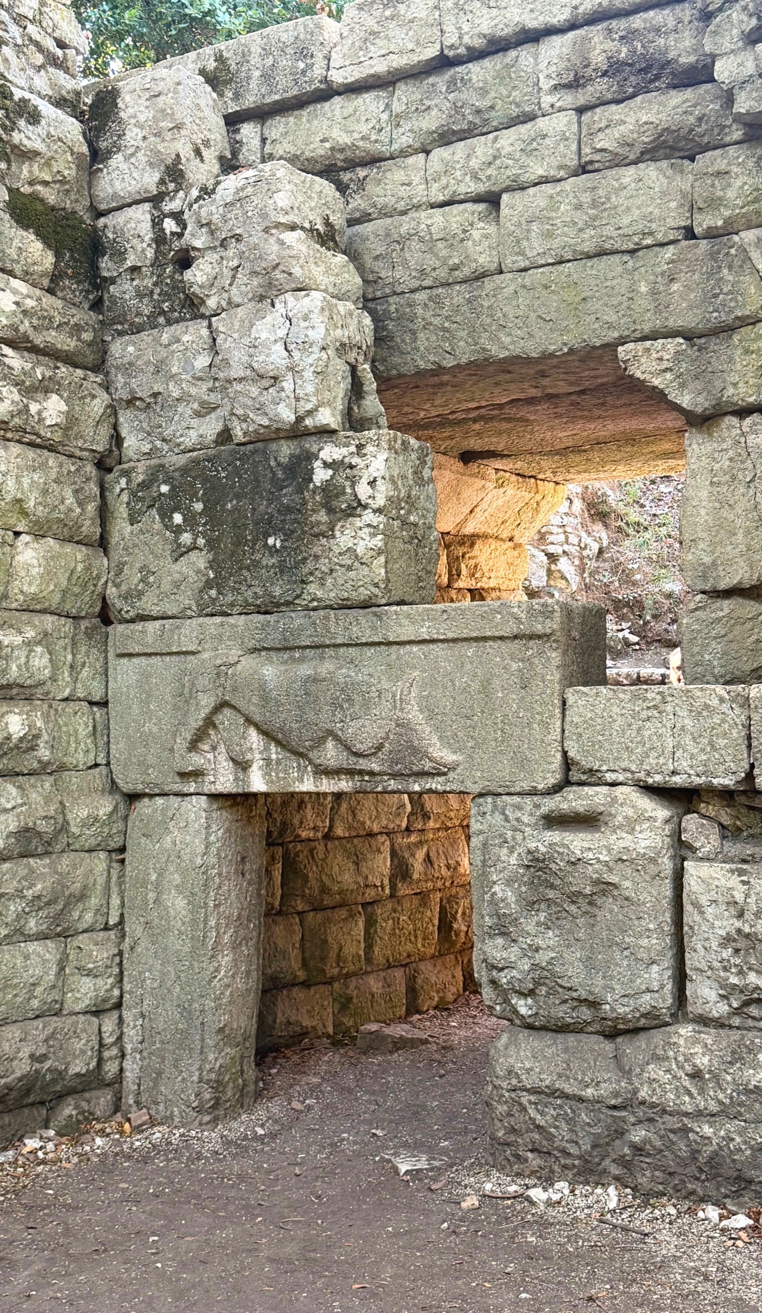 The Lion Gate at Butrint with a carved relief of a lion attacking a bull above the narrow stone entrance.