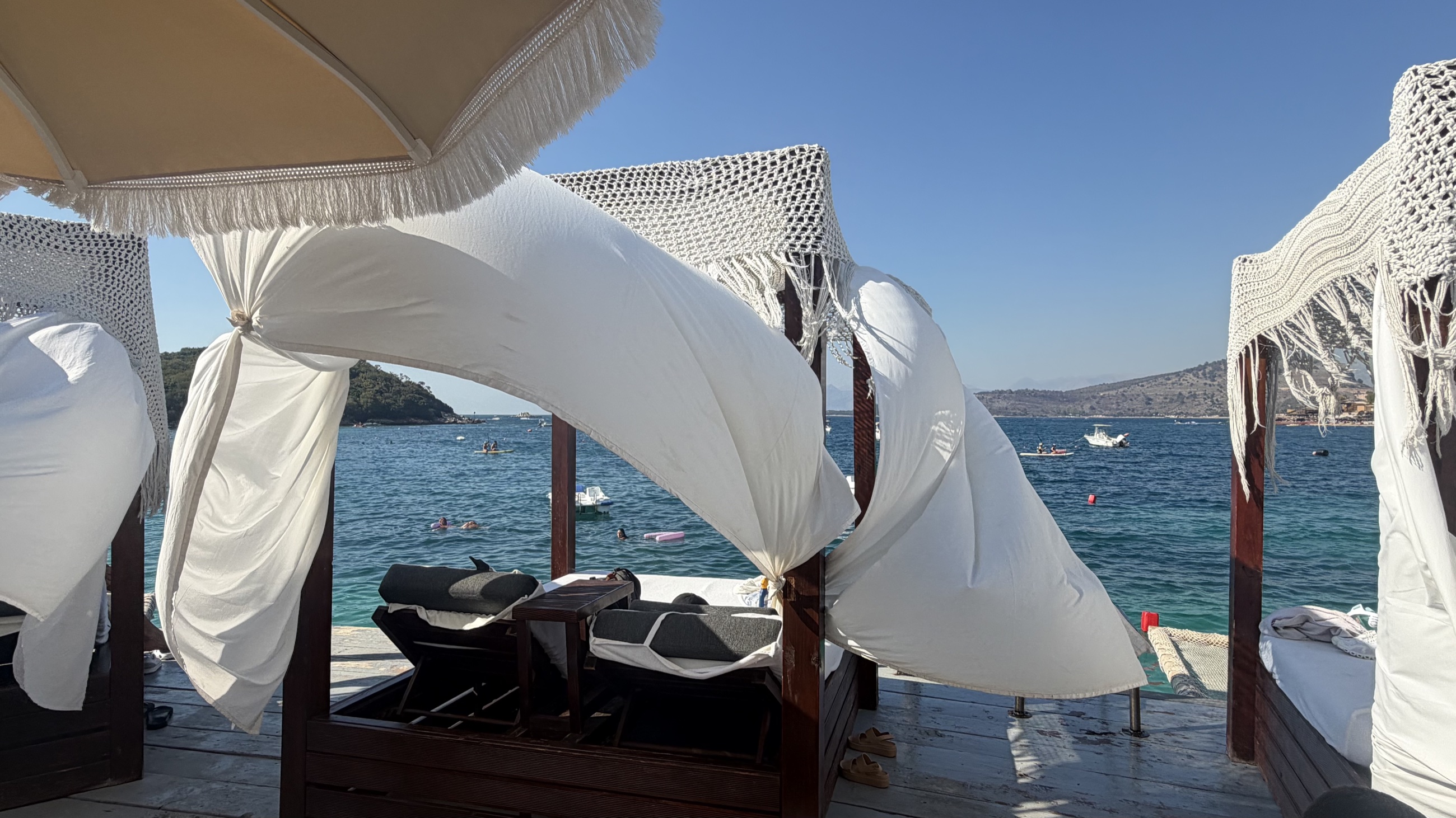 A breezy white-draped cabana beside the water at Ksamil.