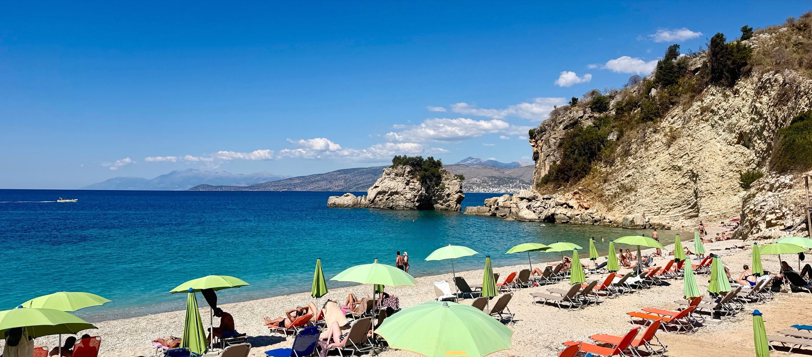 Blue water and beach loungers beneath the cliffs at Mirror Beach.