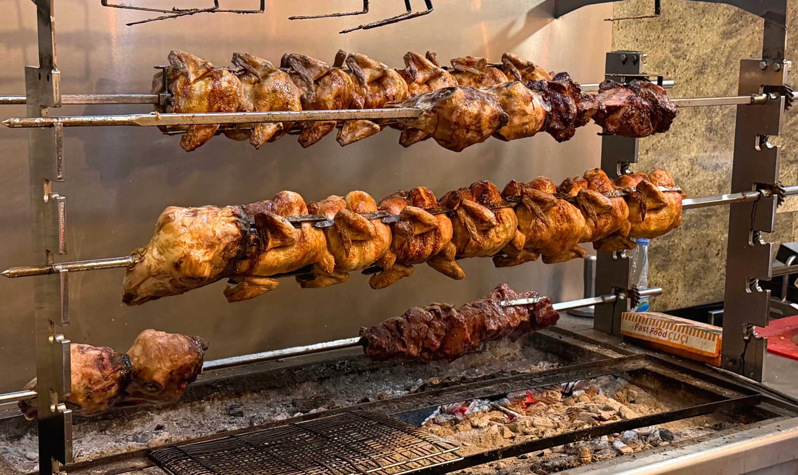 Meat roasting on spits over glowing coals at Cuci.