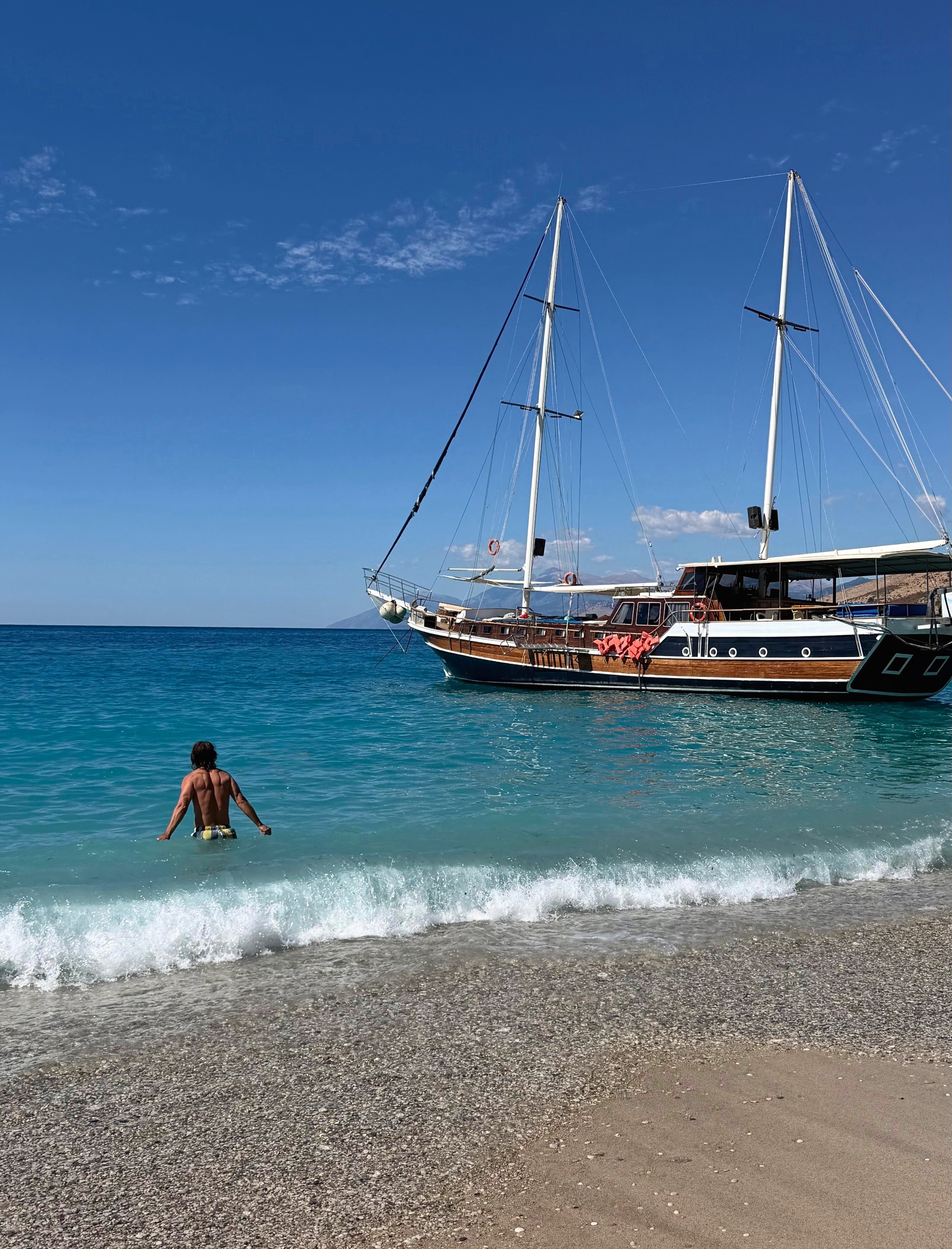 Sam entering the sea at Krorëza with a wooden excursion boat offshore.