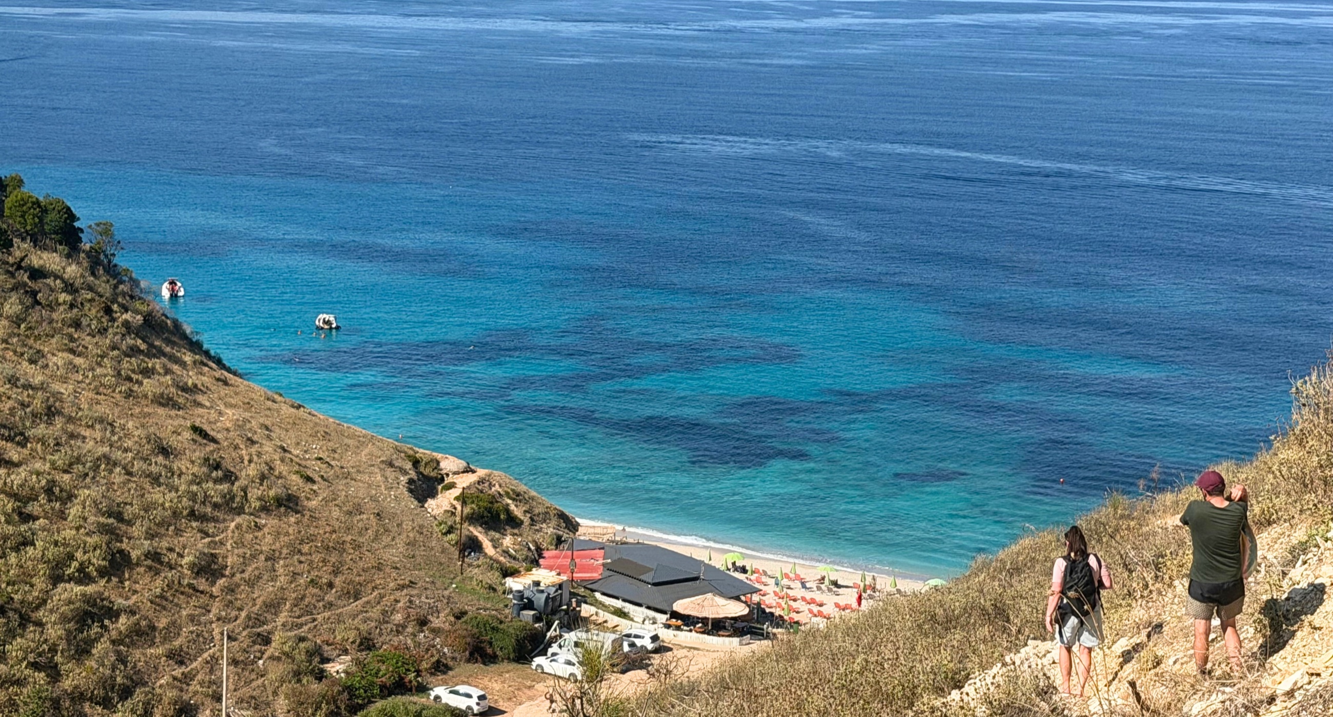 Mirror Beach and its blue water viewed from the hillside path above.