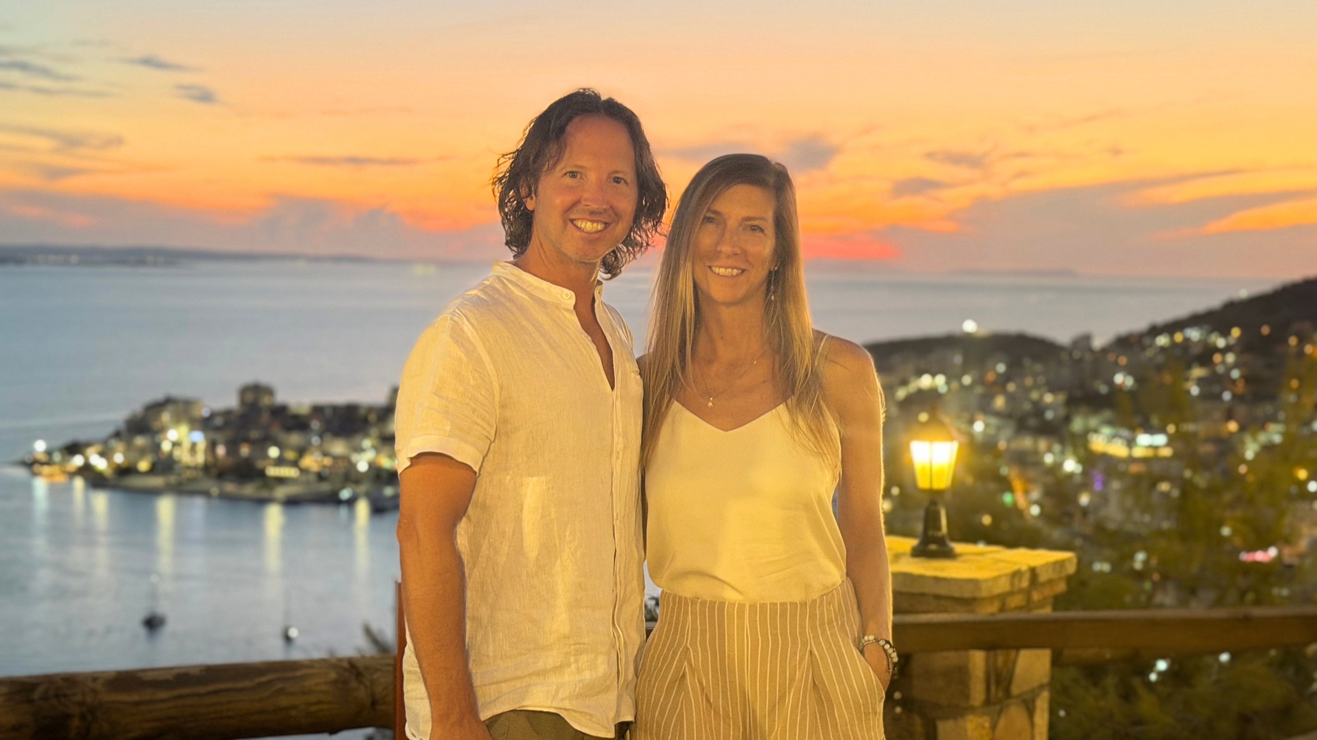 Sam and Stephanie at Kristiano Wine Bar with Sarandë Bay behind them at sunset.