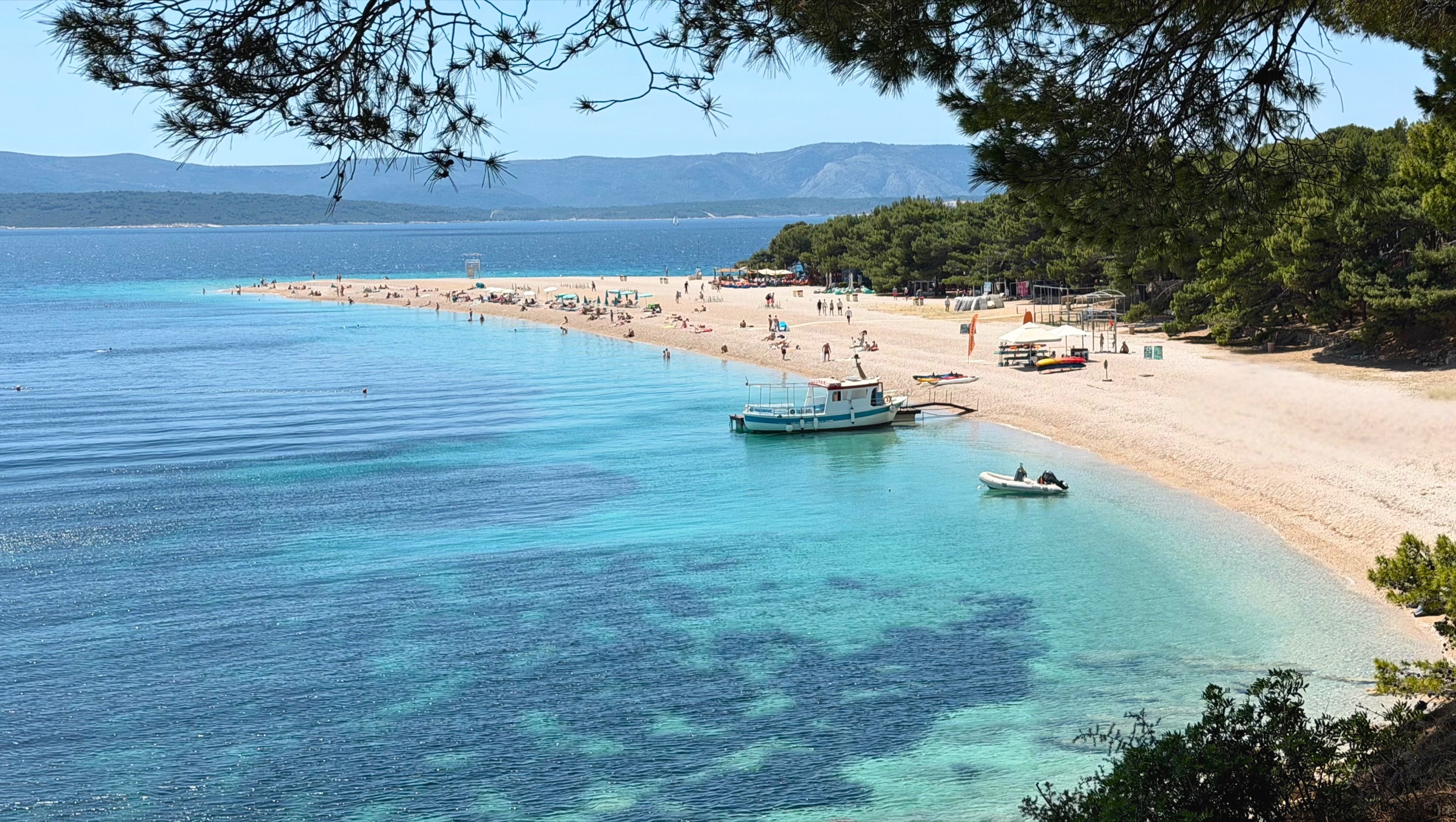 Zlatni Rat beach on Brač with clear Adriatic water and people along the shore.