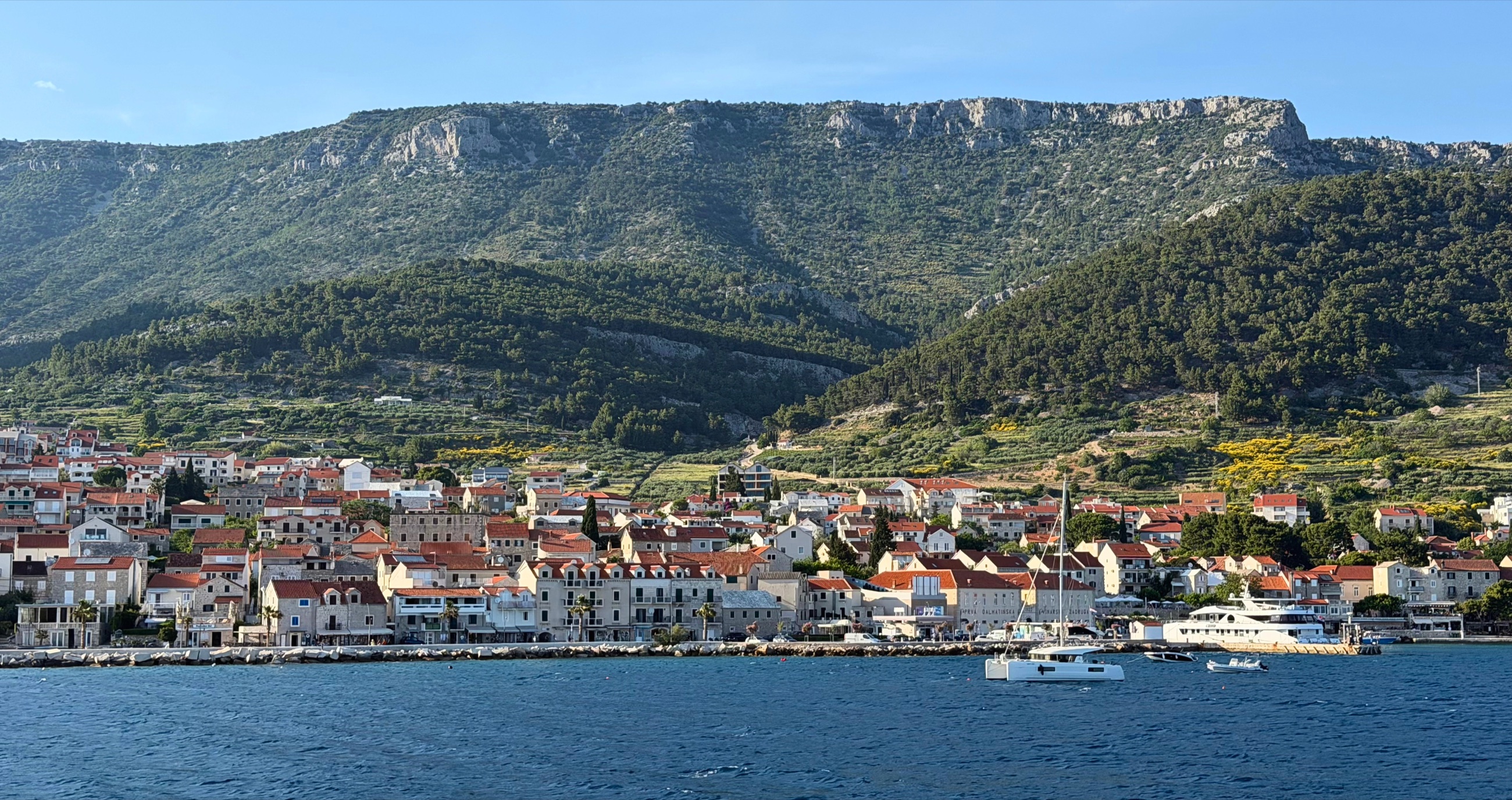 Bol on Brač viewed from the water with green slopes behind the town