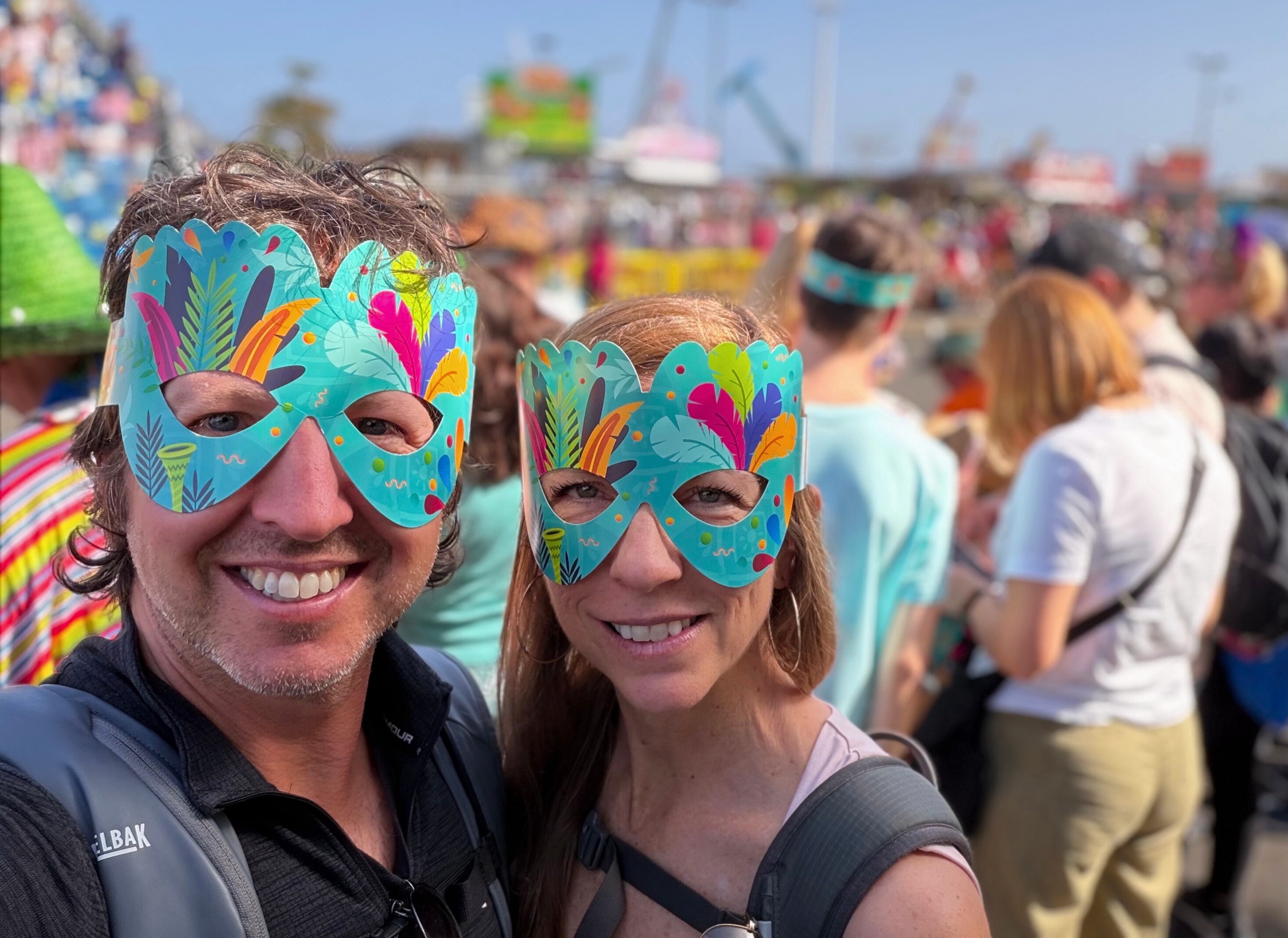 Sam and Stephanie wearing Carnival masks in the crowd at Santa Cruz Carnival.