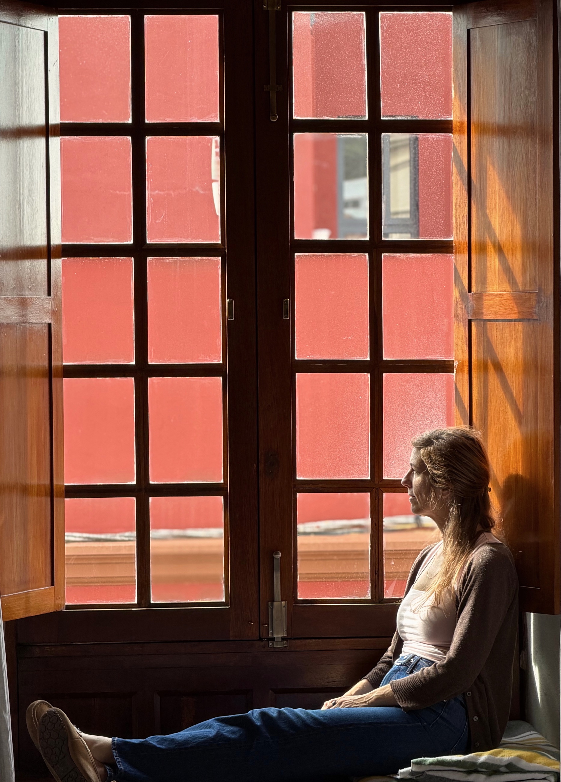Stephanie sitting beside a tall wooden window in the second La Laguna apartment.