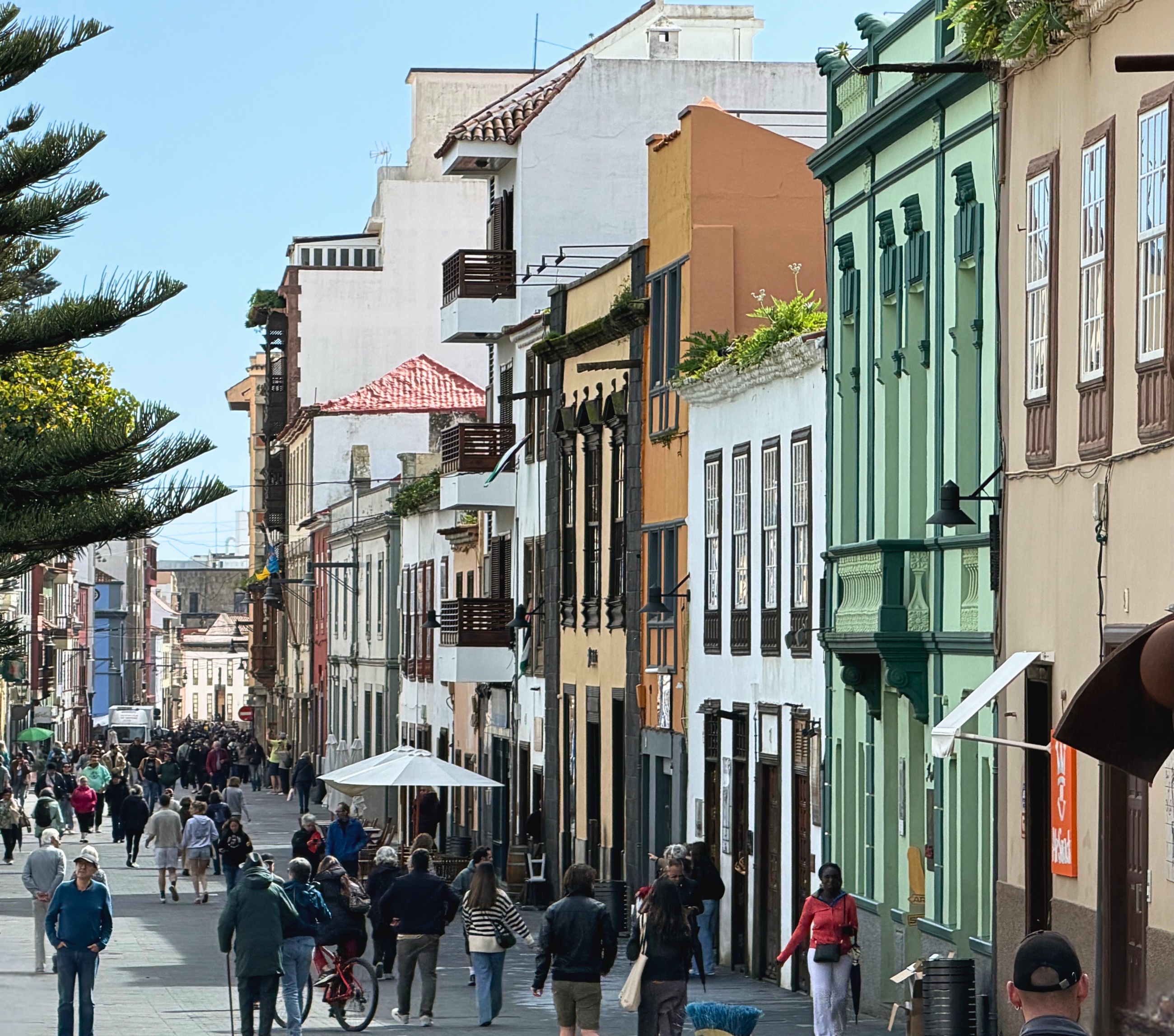 A busy pedestrian street in La Laguna lined with colorful historic buildings.