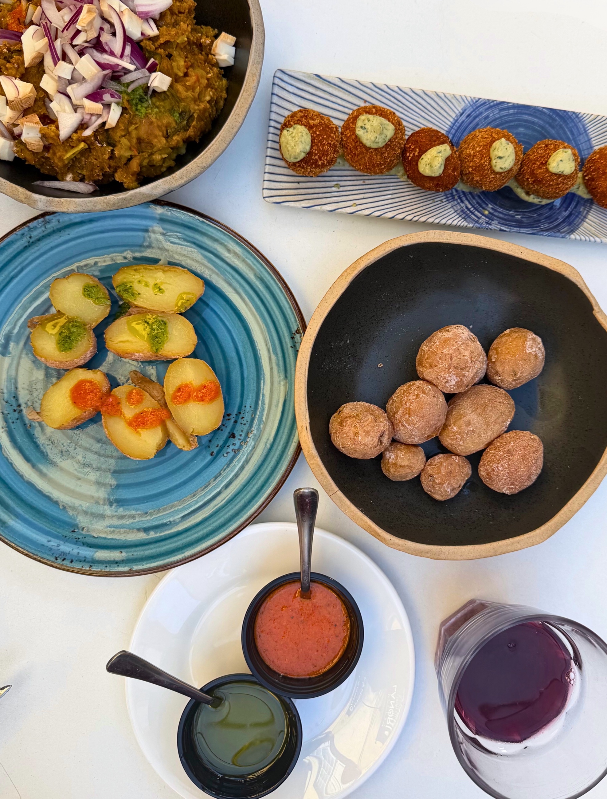 Canarian tapas with papas, mojo sauces, croquetas, gofio, and sangria on a table.