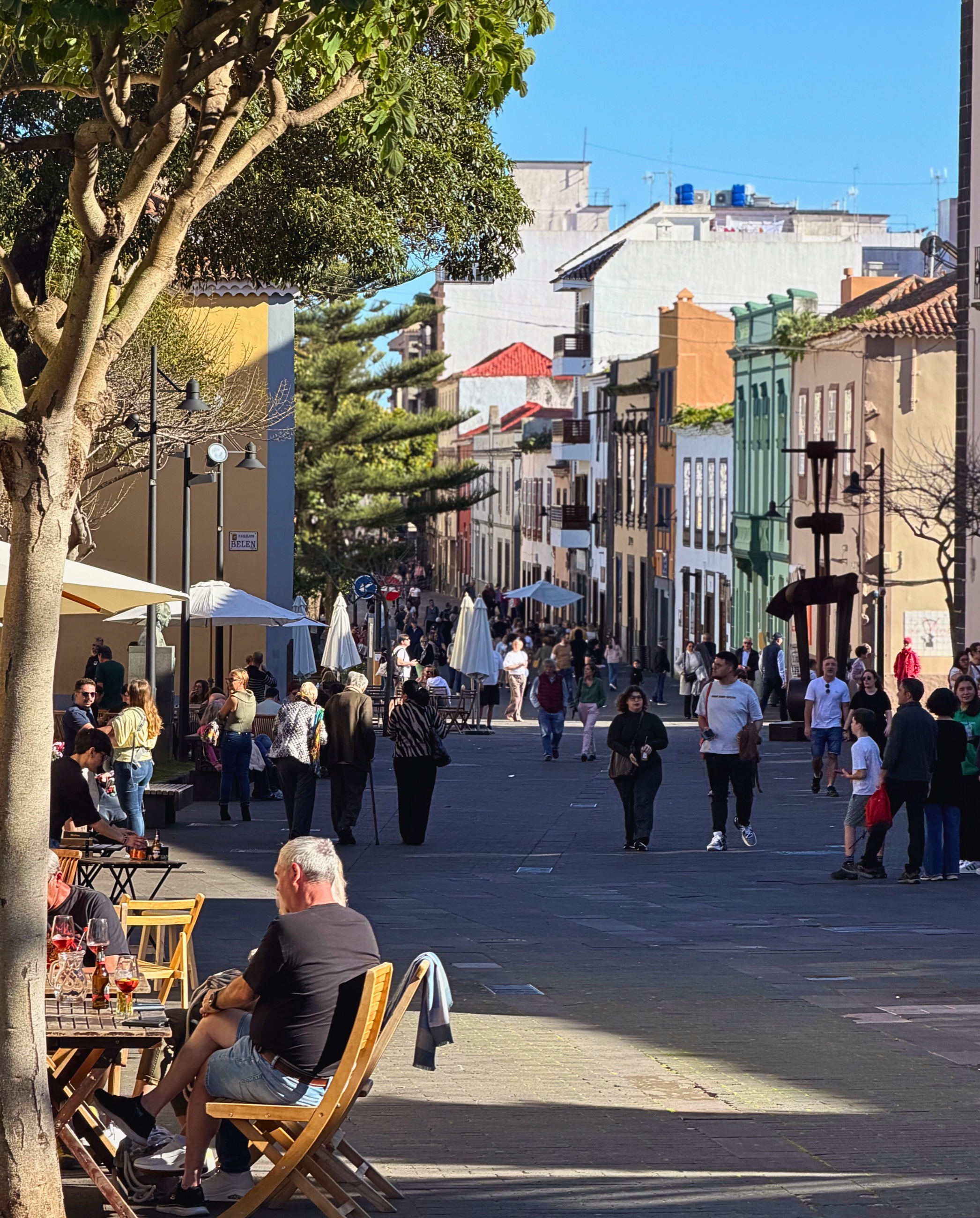 A late-afternoon street scene in La Laguna with cafés and people gathered outside.