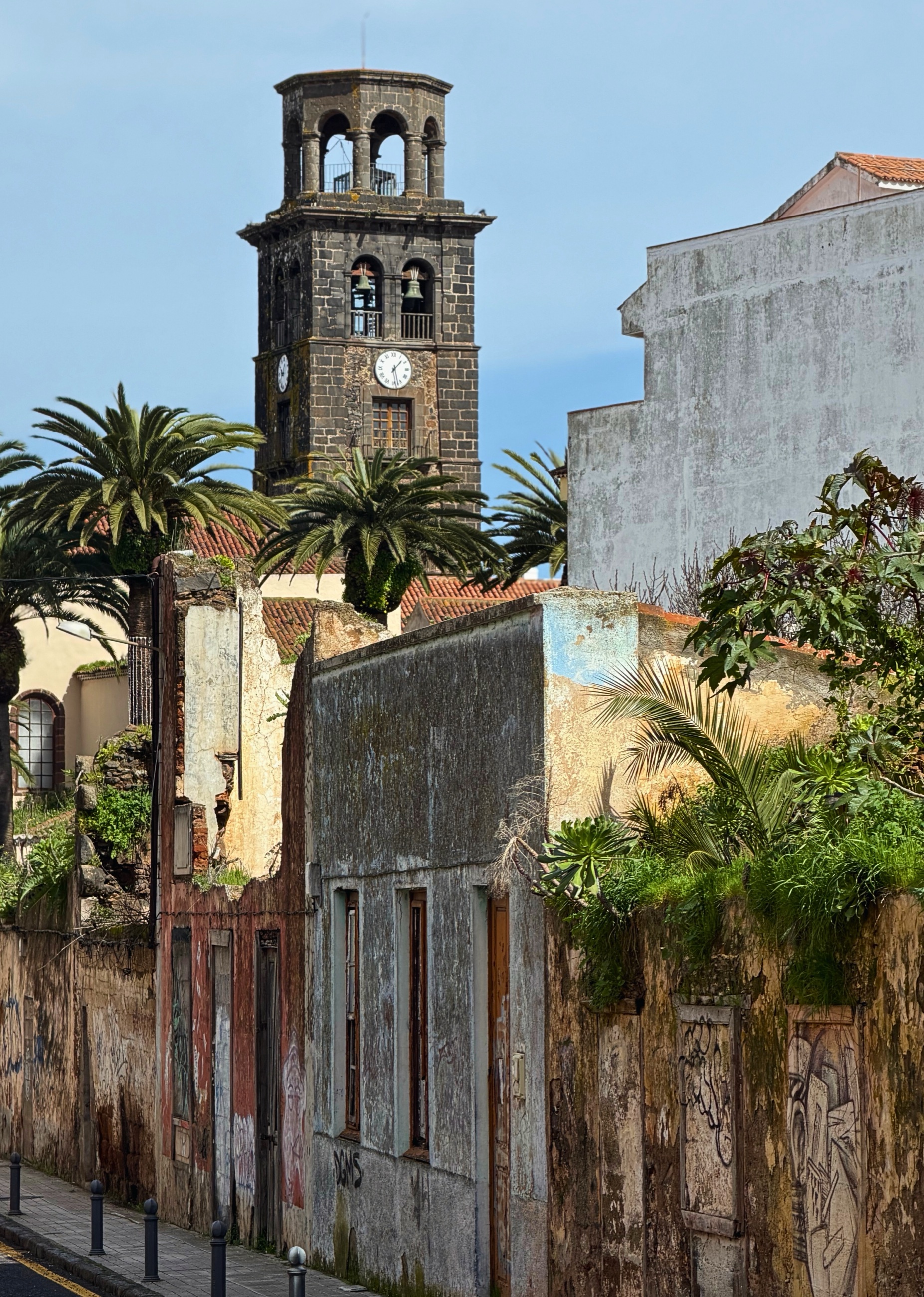 A weathered street corner in La Laguna with the church tower in the background.