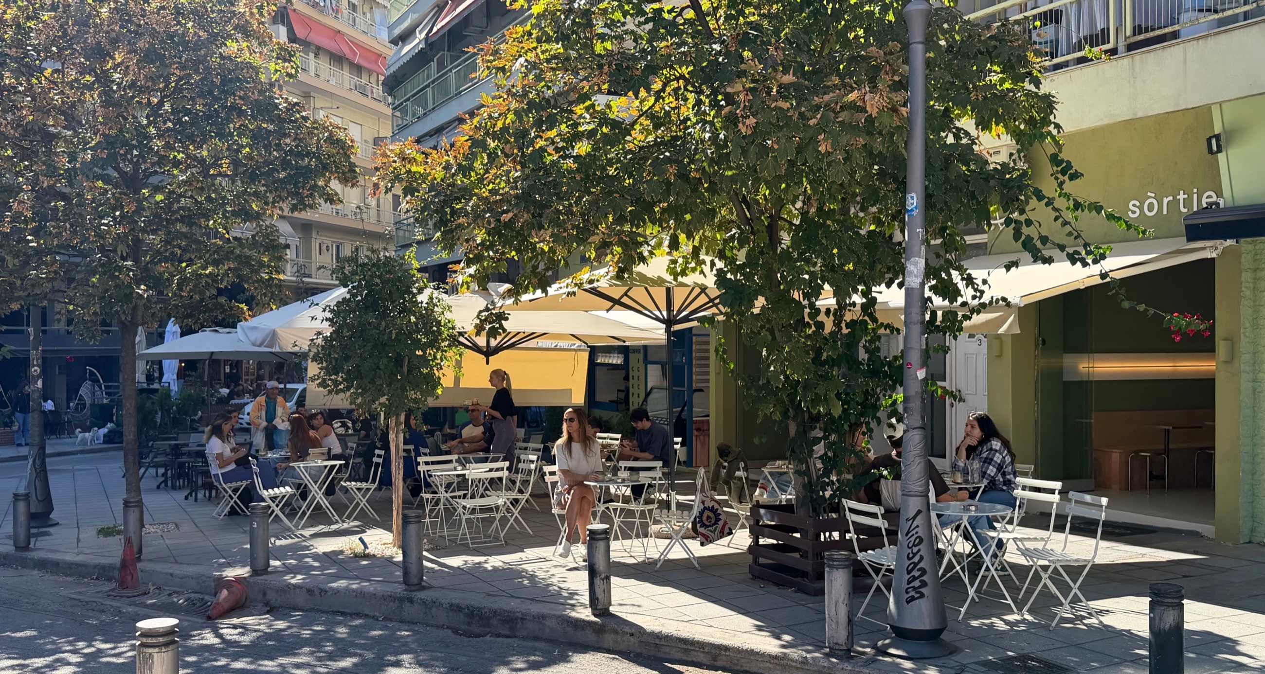 Outdoor tables at Sortie café on a shaded Thessaloniki sidewalk