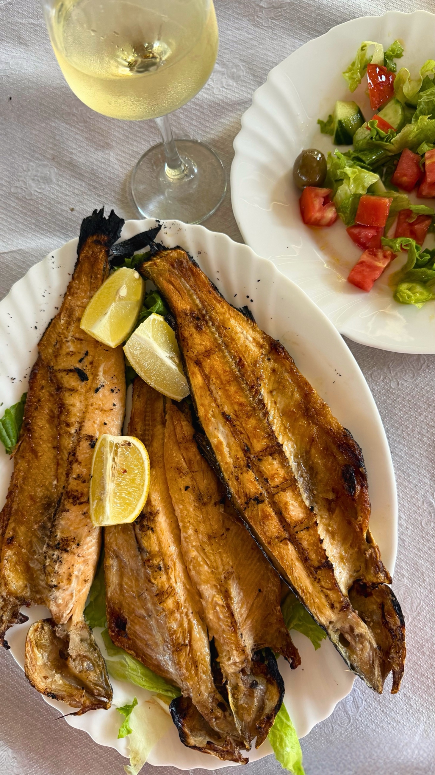 Grilled koran trout served with lemon, salad, and white wine in Pogradec.